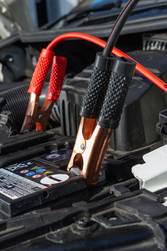Close-up view of jumper cables charging a car battery. Never Get Stuck with a Dead Battery Again. Battery Testing & Replacement with a 24-Month/24,000-Mile Warranty