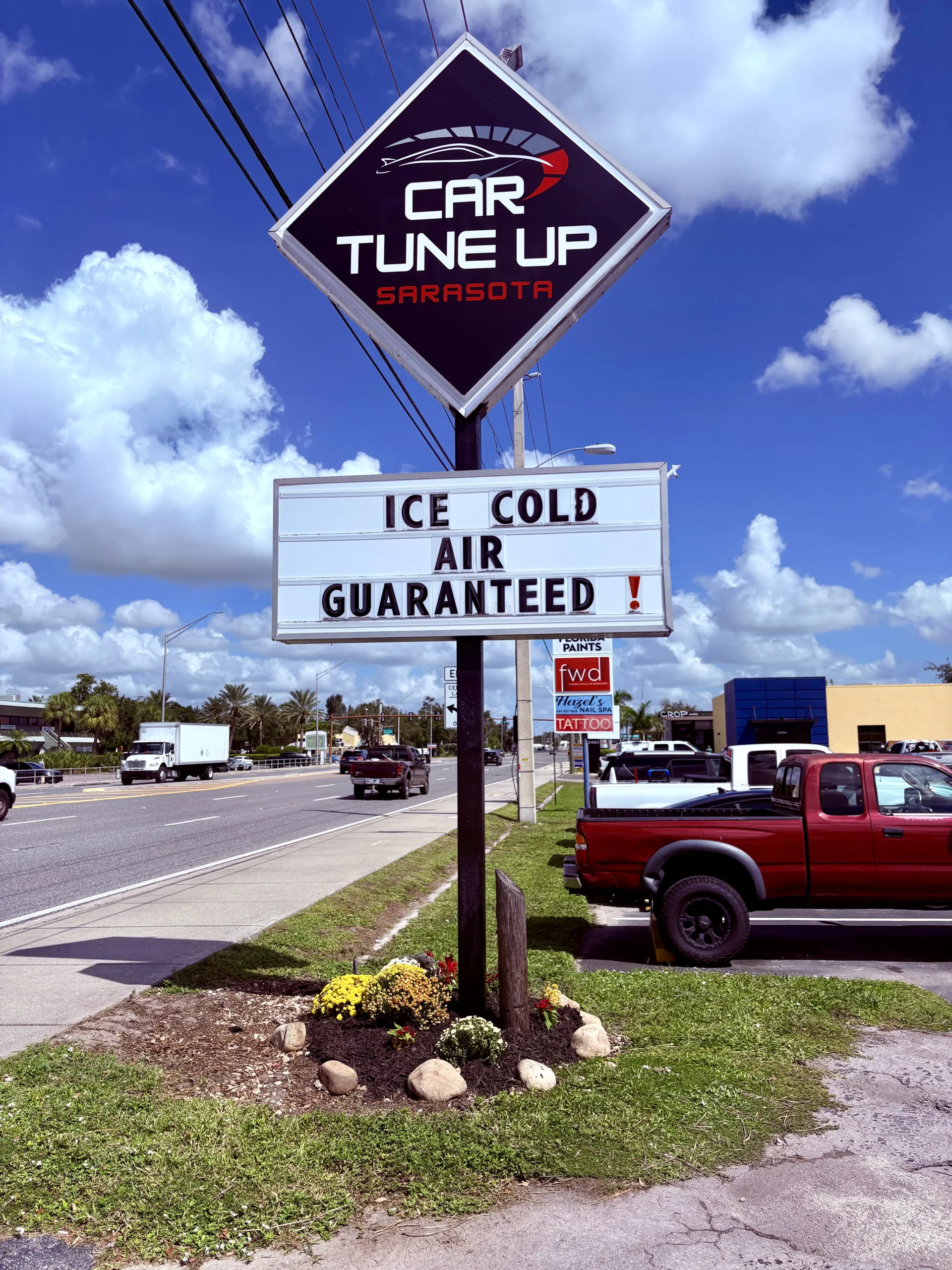 Car Tune Up Sarasota auto repair shop roadside sign on Stickney Point Road promoting ice cold air conditioning guaranteed for Sarasota drivers
